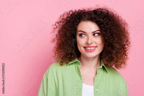 Portrait of optimistic nice girl with wavy hairdo wear green shirt look at proposition empty space isolated on pink color background