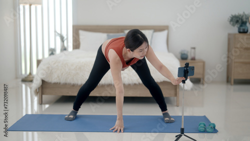 Pregnant woman doing yoga exercises on mobile phone