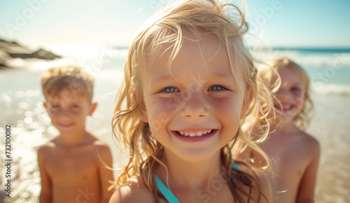 sensitive face portrait of beautiful blonde hair little girl with grey eyes clean skin smiling and staring with sister brother at camera on ocean sandy vacation day. Kids' beauty,fashion and skin care © Soloviova Liudmyla