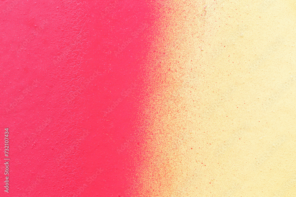Macro close-up of a wall spray painted with pink and yellow. Abstract full frame textured splattered graffiti background with copy space.