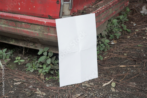 white blank poster for mockup on a damaged car in an abandoned forest, red background, landscape (ID: 732109426)