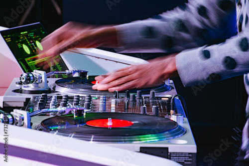 The motion-blurred hands of an African-American DJ spinning records at a mixer. photo