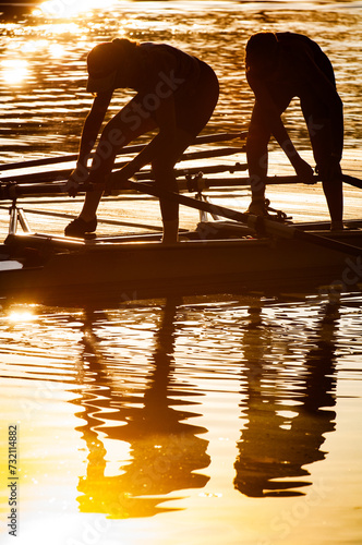 Rowers unloading boats into a river at sunrise photo