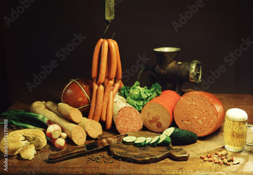 Piece of cooked ham isolated on wooden background with tomato, Italian food, various salami with sausage, bread and mortadella, glass of beer