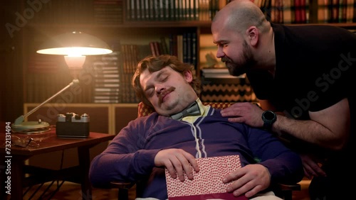 man sleeping in chair in vintage clothes, another guy comes up and kiss his sleeping friend. man is shocked and screams because he is being seduced by another man. photo