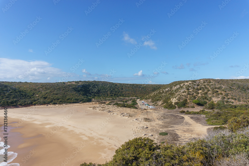 View over the beach of Praia do Barranco with camper vans and a blue sky, Sagres, Algarve, Portugal