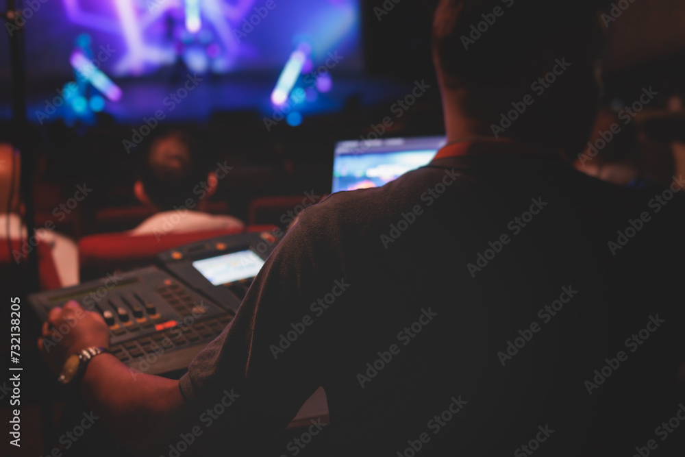 View of lighting technician operator working on mixing console