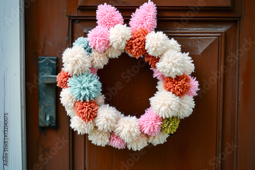 an easter wreath with bunny ears, made out of colorful pompoms, on the outside of the front door of the house