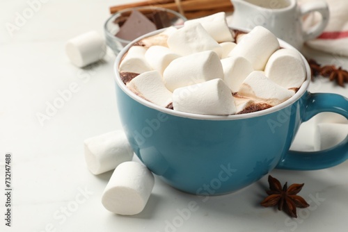 Tasty hot chocolate with marshmallows and ingredients on white table, closeup. Space for text