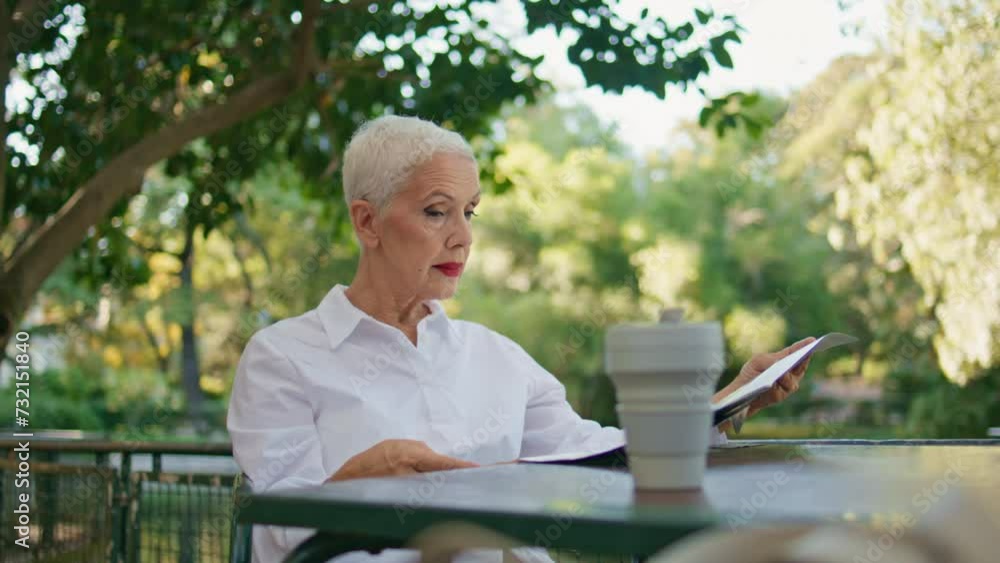 Successful senior reading newspaper on cafe terrace. Elegant woman rest in park Successful senior reading newspaper on cafe terrace. Elegant woman rest in park