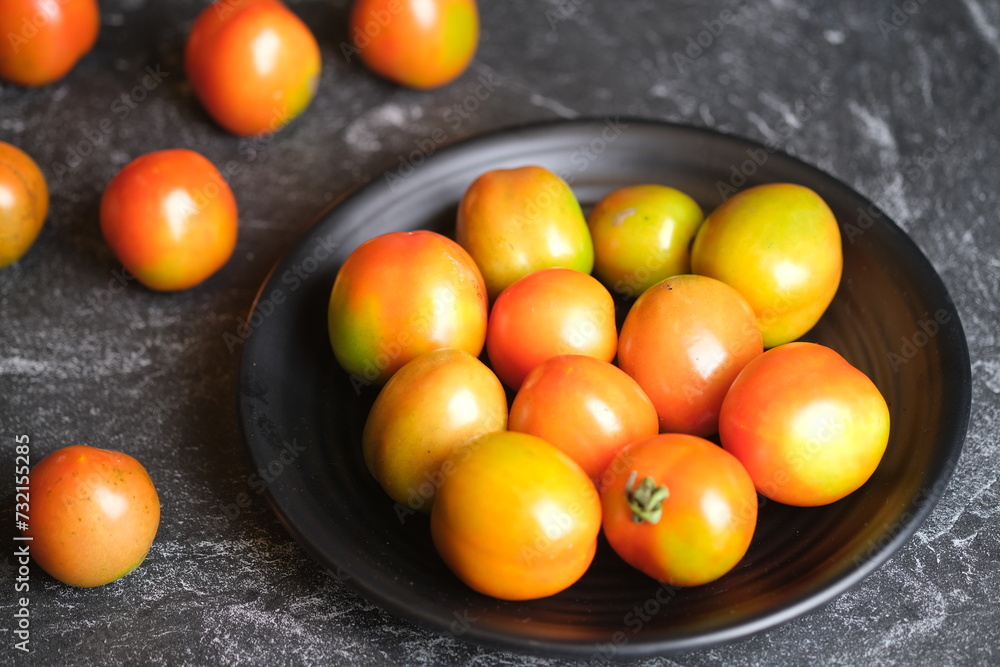 Tomatoes or rangam are plants from the Solanaceae family, plants native to Central and South America, from Mexico to Peru. tomatoes in a black plate. Solanum lycopersicum Tomatoes or rangam are plants from the Solanaceae family, plants native to Central and South America, from Mexico to Peru. tomatoes in a black plate. Solanum lycopersicum