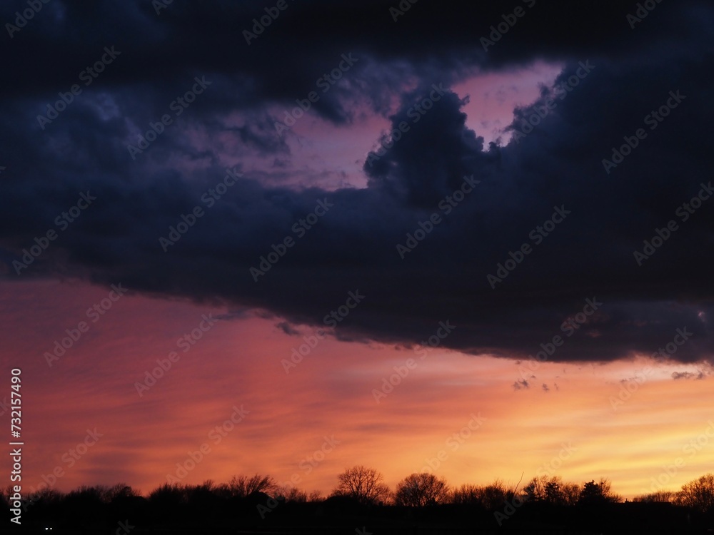 Towering cumulus clouds in foreground with salmon-colored sky in background during a Kansas sunset. 