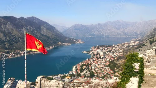 View of the Bay of Kotor from Kotor Fortress with the Montenegro flag blowing in the wind. Aerial view of Kotor old town. Kotor, Montenegro. Europe.