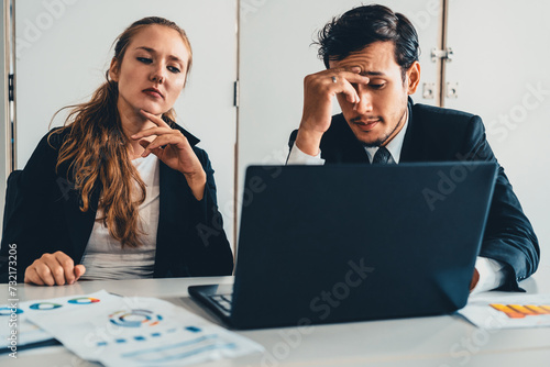 Unhappy serious businessman and businesswoman working using laptop computer on the office desk. Bad business crisis situation and bankruptcy concept. uds