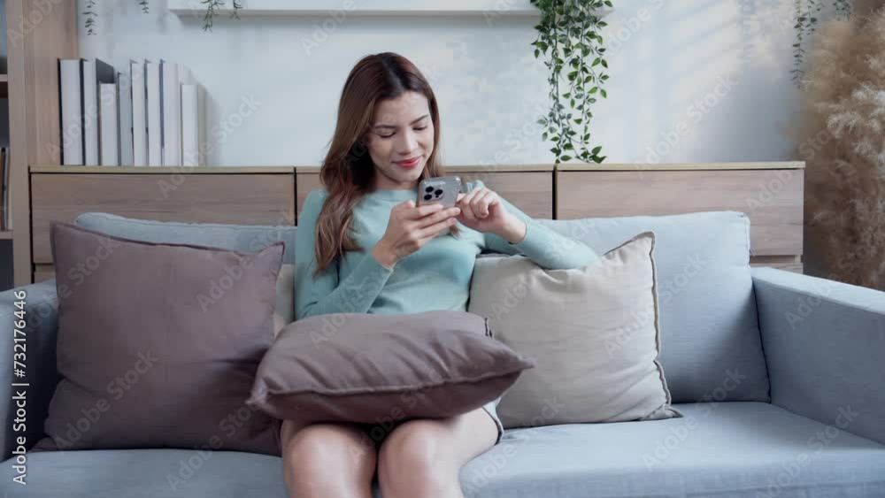A young woman is relaxing on the sofa in the house. Spend the holiday watching movies, listening to music, and scrolling through social media on your smartphone. A young woman is relaxing on the sofa in the house. Spend the holiday watching movies, listening to music, and scrolling through social media on your smartphone.