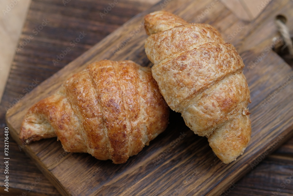 whole wheat croissants on wooden cutting board. croissant, which originated in France, is so named because of its shape resembling a crescent moon. made from wheat, eggs, salt, margarine.