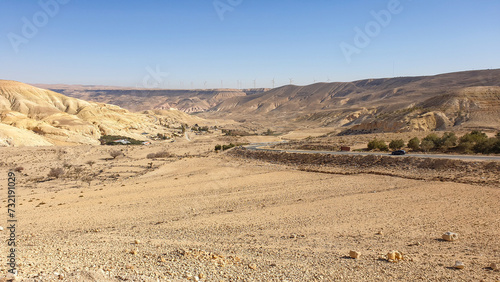 Scenic panoramic view of mountainous desert terrain with wind turbine farm in distance in Jordan, Middle East