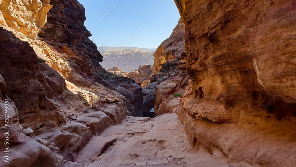 Scenic landscape view of hidden walkway through red rocky mountainous desert terrain in the ancient city of Petra, Jordan