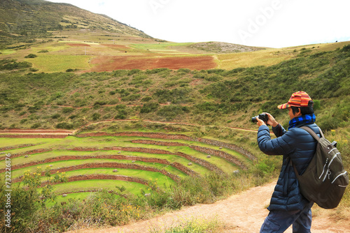 Traveler taking photos of the remains of Moray, an Incan agricultural terraces in Sacred Valley of the Incas, Cusco Region, Peru, South America