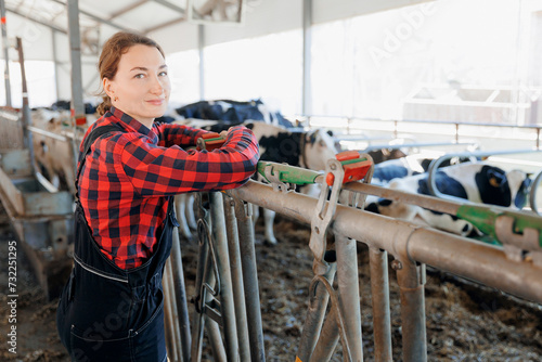Happy smiling young woman farmer plaid shirt and uniform on background cows dairy farm. Agriculture Farming livestock cattle industry