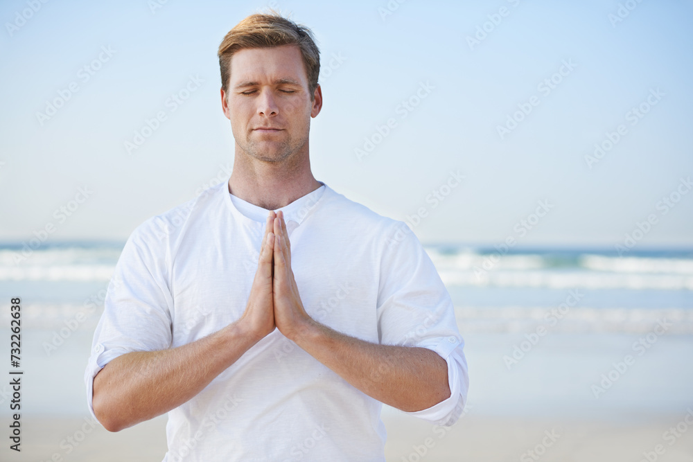 Man, meditation on beach and prayer for zen, wellness and holistic healing outdoor for calm and yoga. Ocean, fresh air and travel with mindfulness for peace of mind, wellbeing and spiritual in nature
