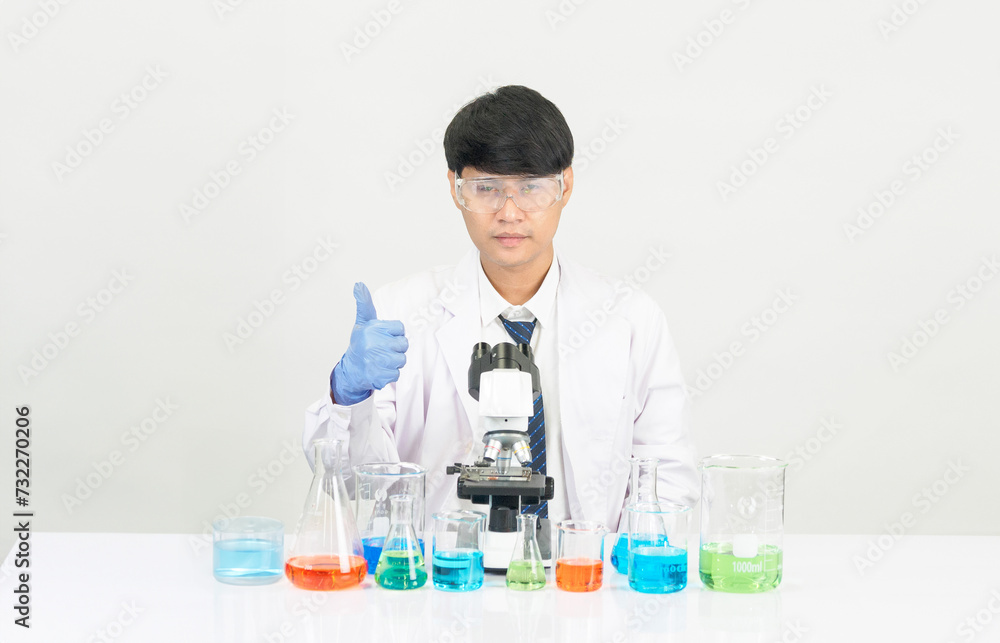 Portrait asian man student scientist Wearing a doctor gown in the lab looking hand at chemist. caused by mixing reagents in scientific research laboratories with test tubes and microscope on the table Portrait asian man student scientist Wearing a doctor gown in the lab looking hand at chemist. caused by mixing reagents in scientific research laboratories with test tubes and microscope on the table