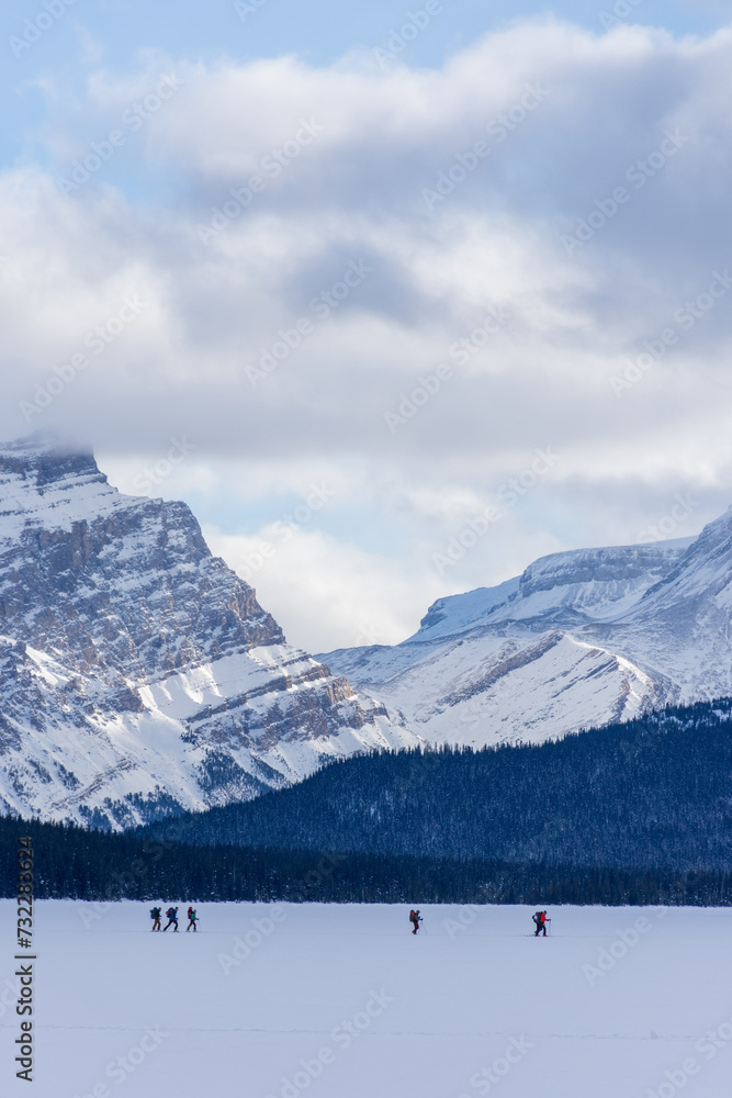 Group of cross country skiers seen from afar in front of the snowy Canadian Rocky Mountains in the Banff National Park