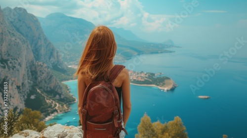 A young woman stands with her back and admires the view of the sea and mountains. A traveler traveling on vacation in the most beautiful place in the world. Summer vacation