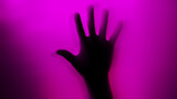 Hand silhouette on purple background. Blurred human hand shape out of focus