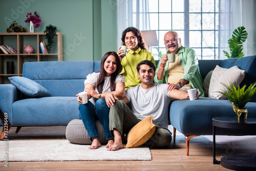 Cheerful Indian family enjoying tea or coffee together, looking at the camera © StockImageFactory
