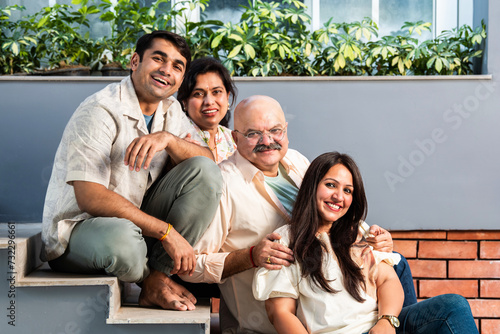 Outdoor portrait of cheerful Indian family sitting on stairs. © StockImageFactory