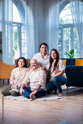 Portrait of happy Indian family of four sitting in modern living room