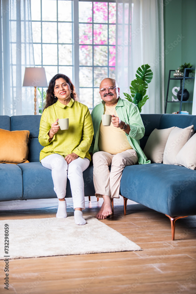 Indian Cheerful old couple having coffee at home while sitting on sofa or staircase Indian Cheerful old couple having coffee at home while sitting on sofa or staircase