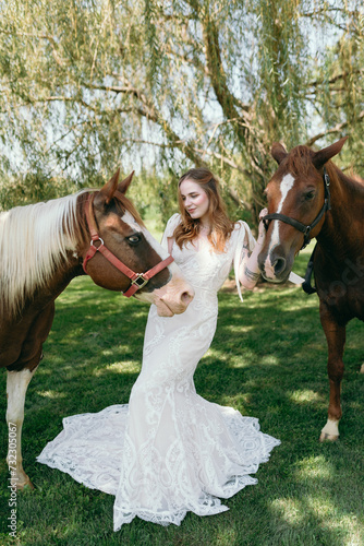 Two pet horses with bride in a lace wedding dress