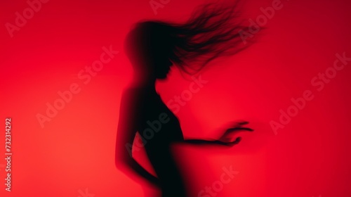 Female blurred silhouette on a red background. Elegant outline of a woman in motion out of focus