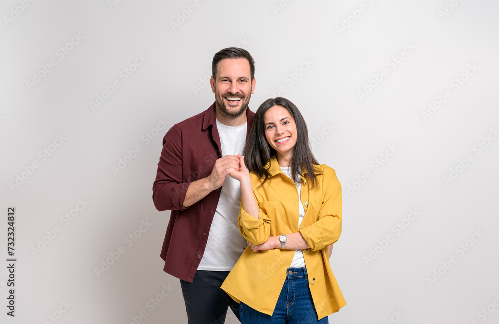 Portrait of romantic young boyfriend and girlfriend holding hands and smiling on white background Portrait of romantic young boyfriend and girlfriend holding hands and smiling on white background