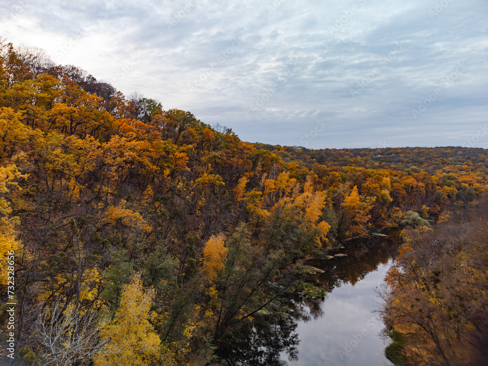 Autumn aerial river valley and colorful golden forest. Flying above autumnal riverside in Ukraine