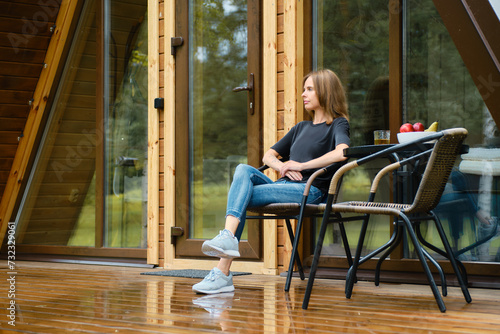 Cute woman enjoys fresh air after the rain in forest cabin