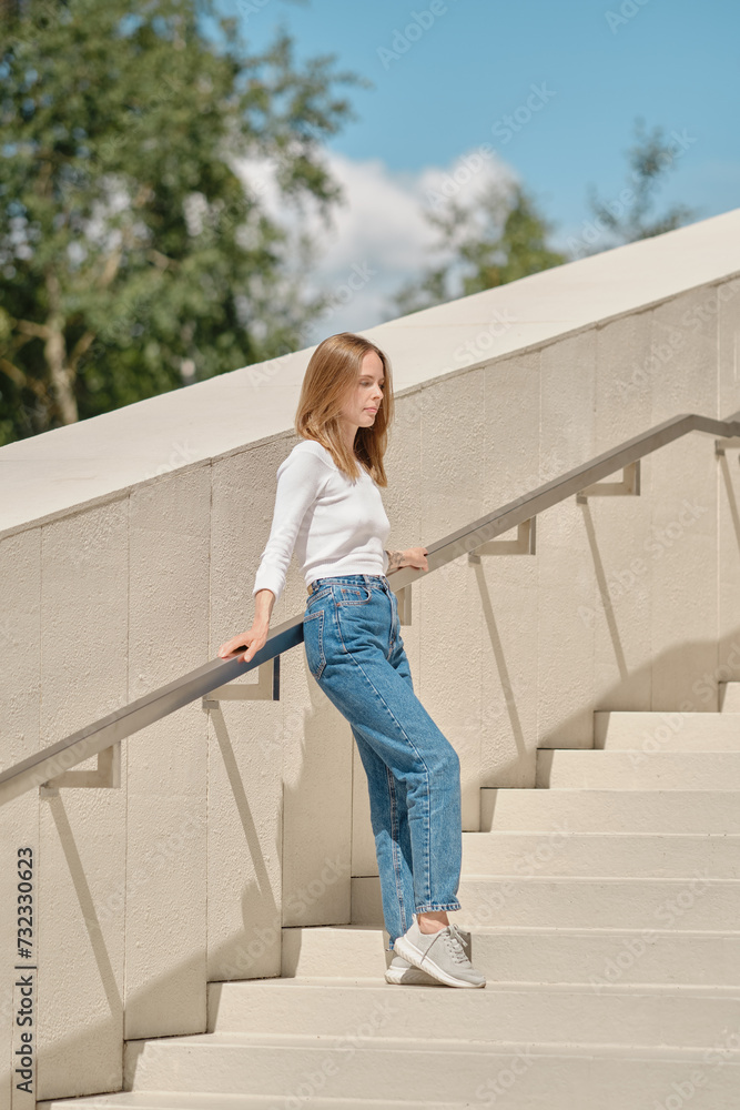 Woman standing with her back against railing on stairs Woman standing with her back against railing on stairs