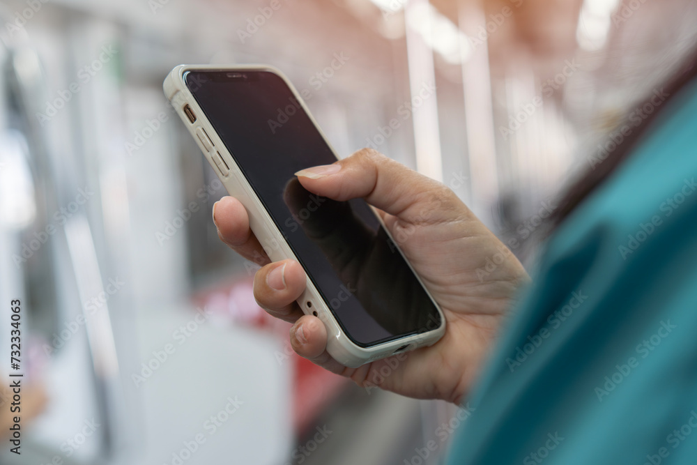 Cropped view of woman using her cell phone on subway platform, message sms e-mail.