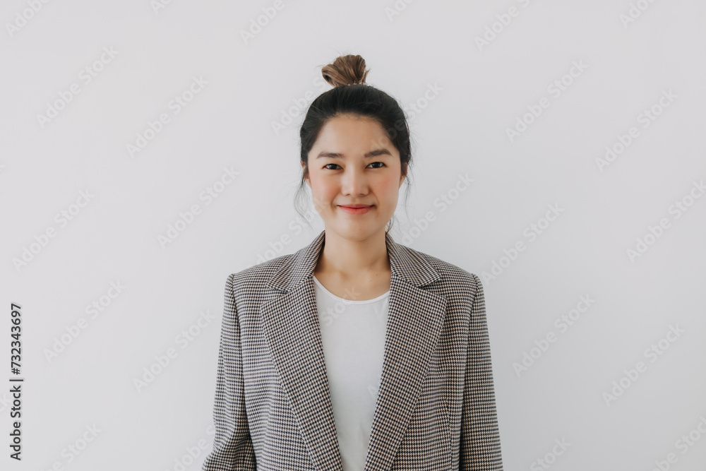 Asian Thai woman smiling and looking at camera, businesswoman wearing blazer suit and bun hairstyle, successful at work, standing isolated over white background wall. Asian Thai woman smiling and looking at camera, businesswoman wearing blazer suit and bun hairstyle, successful at work, standing isolated over white background wall.