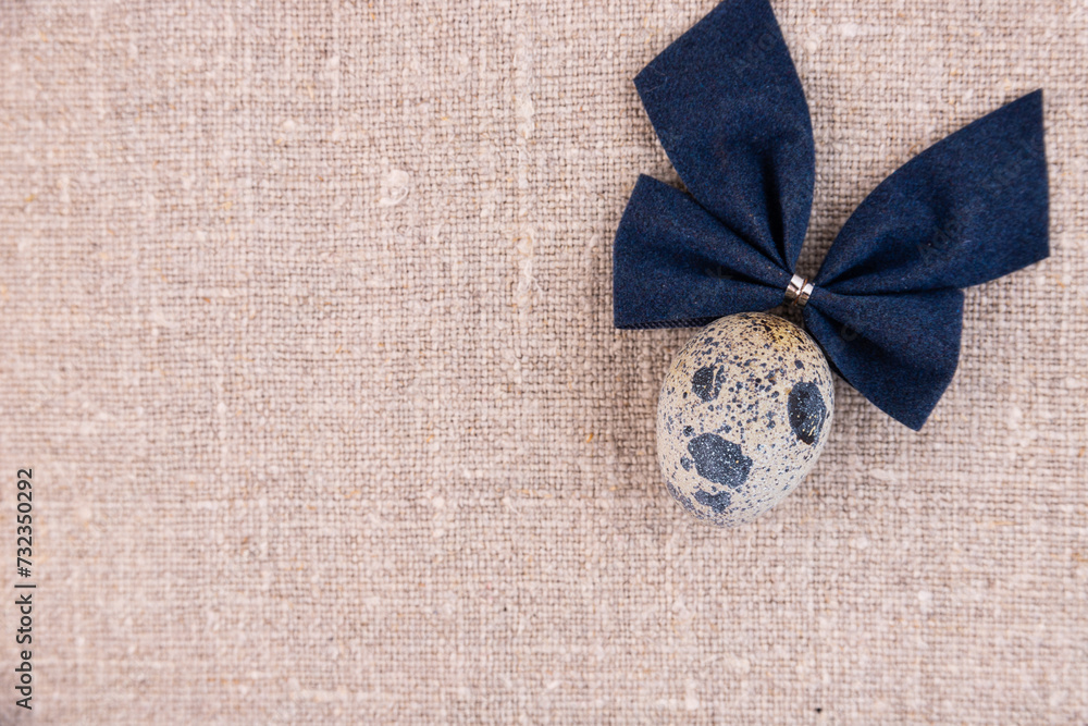 Fototapeta premium Easter composition with egg and bow on a linen surface.