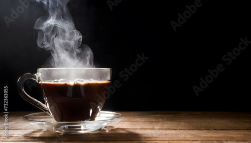 Steaming glass coffee cup on black background and wooden floor. Copy space.