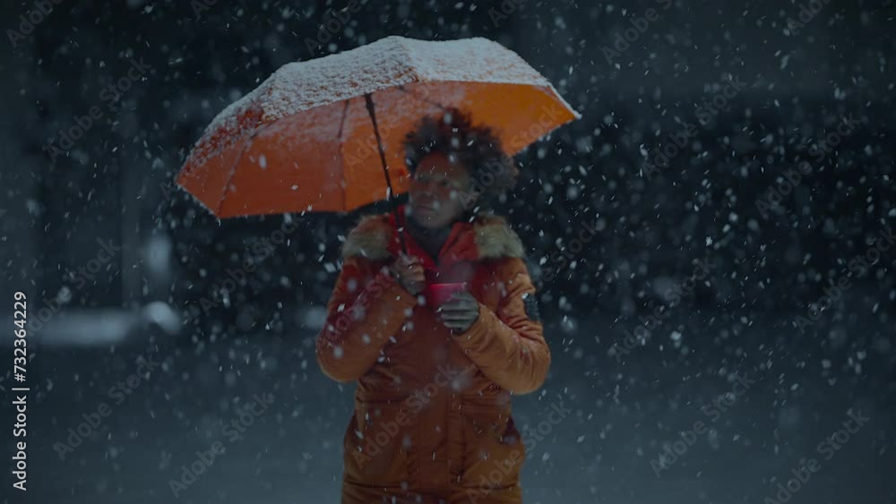 African Woman With Afro Hairstyle In Organge Clothes Outside in Strong Snowfall African Woman With Afro Hairstyle In Organge Clothes Outside in Strong Snowfall