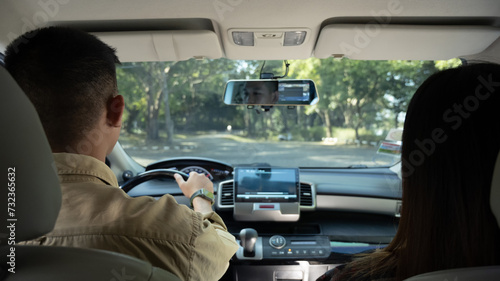 Back view of beautiful young couple driving comfortable automobile on a country road. Travel and vacation concept