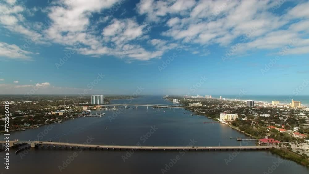 Aerial Shot Of Bridges Amidst Residential City Landscapes, Drone Flying Backwards Over River On Sunny Day - Daytona Beach , Florida Aerial Shot Of Bridges Amidst Residential City Landscapes, Drone Flying Backwards Over River On Sunny Day - Daytona Beach , Florida