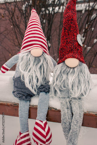 Couple of dwarves on the bench in snow. Romantic gift. Friendship concept. Valentine's Day concept. Gnomes with heart and red hat in snow. Love background. Christmas fairytale dwarves. Winter holidays