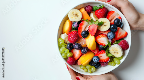 A fresh fruit salad with strawberry, blueberry, peach, banana, and grape on a white background