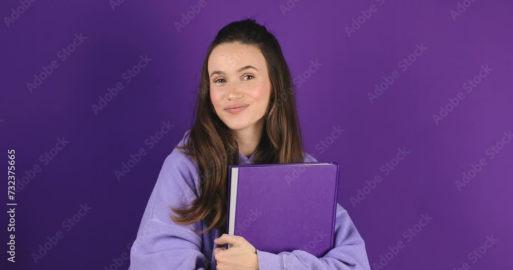 Brunette woman student holding book with happy expression over isolated purple background. Girl smiling and hold book. Love reading concept. Brunette woman student holding book with happy expression over isolated purple background. Girl smiling and hold book. Love reading concept.