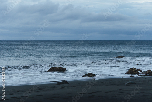 rocky coast of the atlantic ocean in moody atmosphere with black sand beach and waves